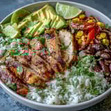 A zesty Cajun Chicken Bowl topped with creamy avocado slices, fresh cilantro, and bright lime wedges ready for serving.