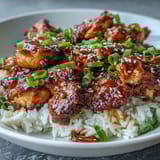 Sticky honey garlic chicken in a rich glaze, served over jasmine rice with sesame seeds and sliced green onions.  
