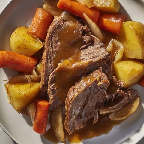 Tender beef pot roast, vegetables glistening in rich gravy, promises a savory, slow-cooked family meal.