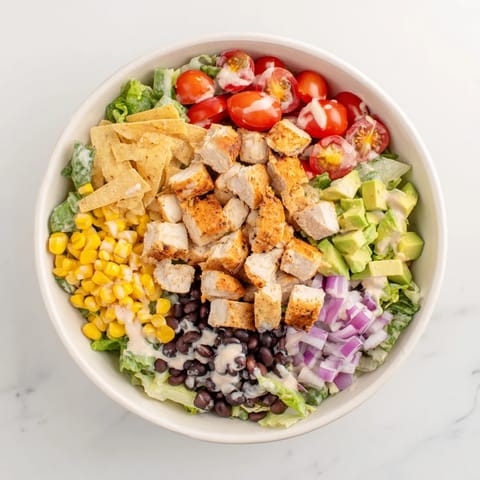 Colorful bowl of Chicken Taco Chopped Salad with seasoned chicken, crisp lettuce, and creamy salsa ranch.  