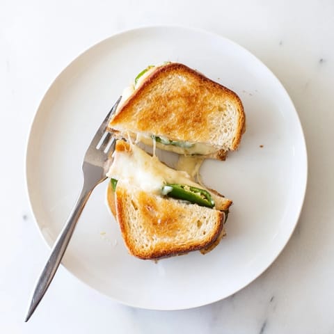 A close-up of a freshly made Jalapeño Havarti Grilled Cheese, oozing creamy cheese between buttery bread.  