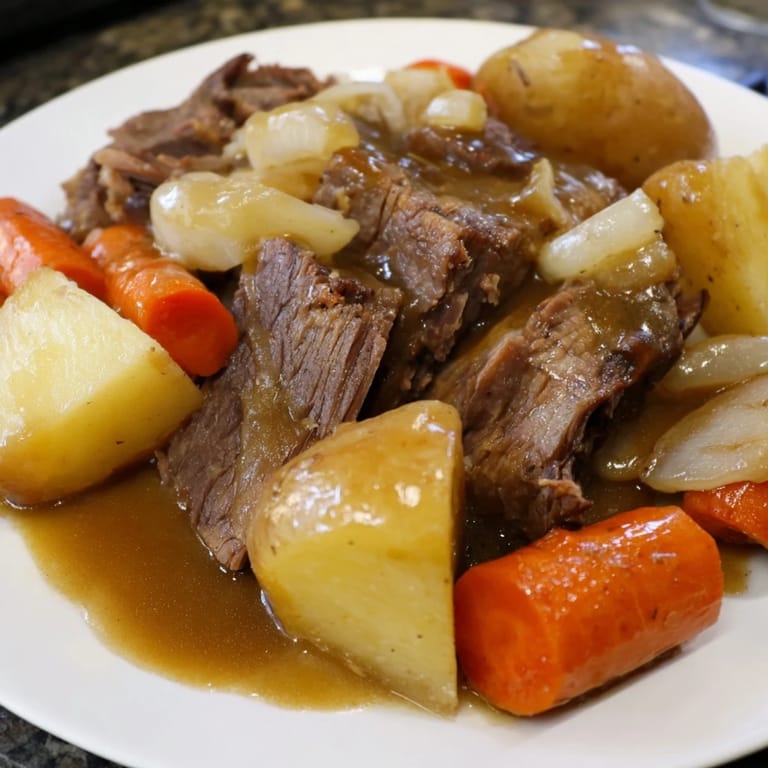 A close-up shot of a comforting beef pot roast, showcasing fork-tender meat and colorful carrots.