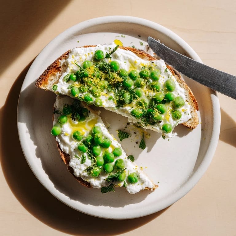 A vibrant open-faced Pea & Mint Ricotta Toast served as a bright brunch centerpiece beside lemon wedges.  
