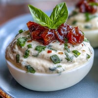 Caprese Deviled Eggs with basil oil, featuring bright tomato and mozzarella.